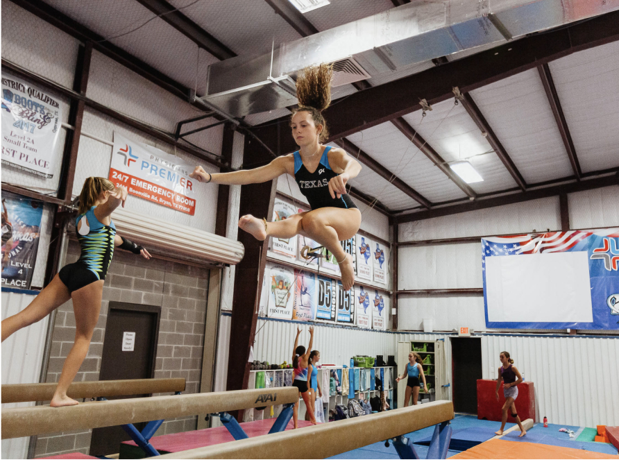female gymnast jumping on balance beam