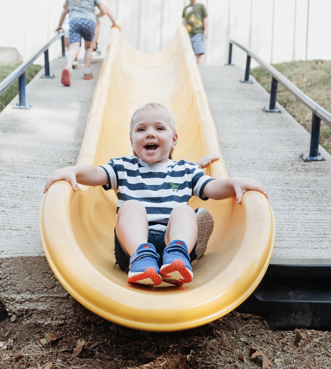 boy smiling while on a slide